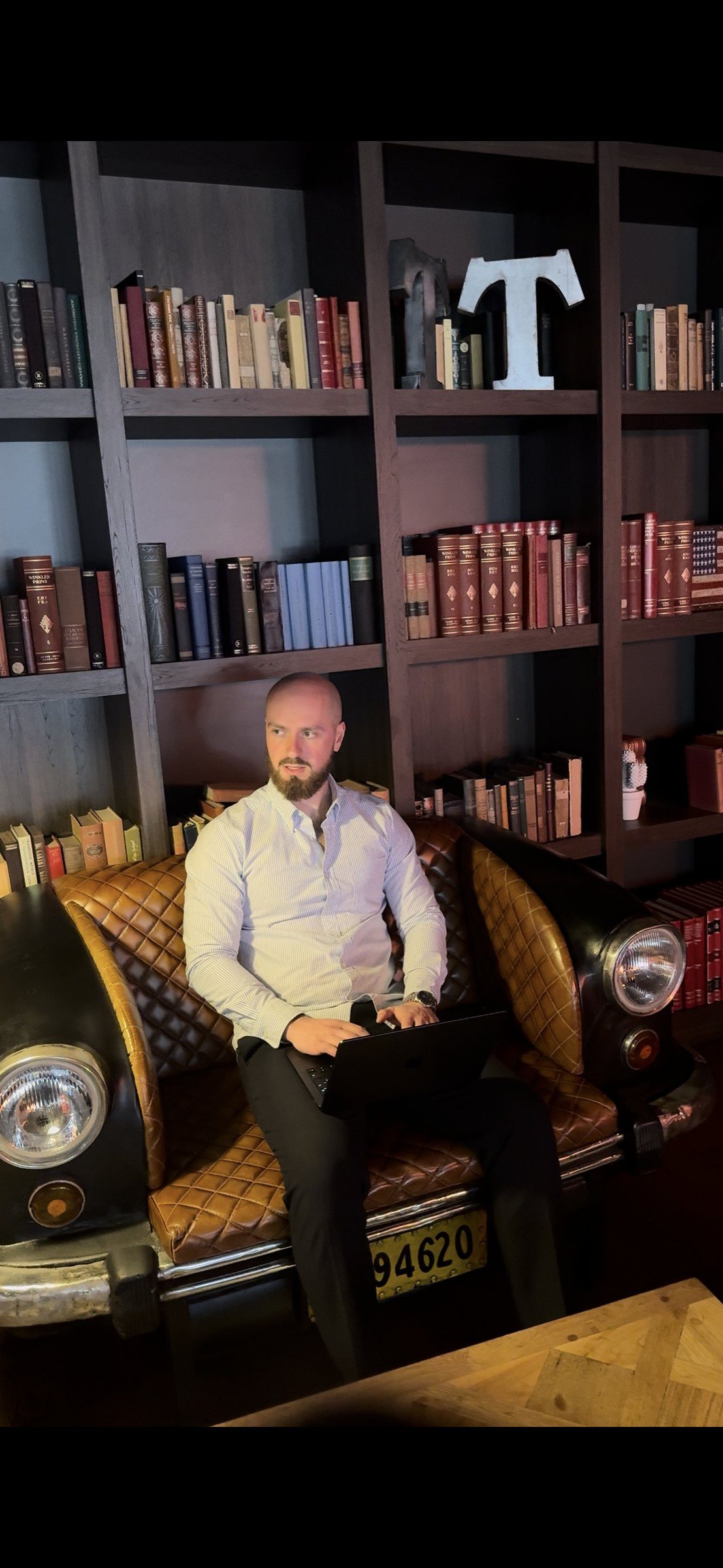 Thomas Marmet assis dans une bibliothèque, ordinateur sur les genoux